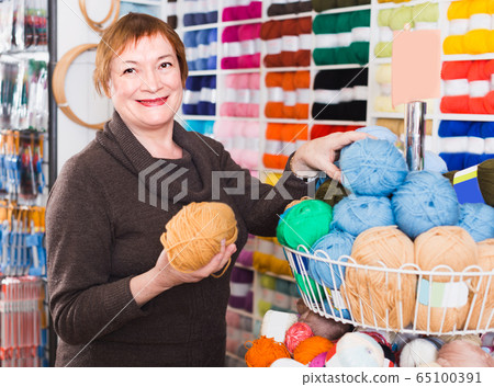 Woman is choosing yarn for knitting at special price Woman is choosing yarn for knitting at special price 65100391