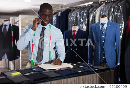 Tailor makes an entry in the book of orders in the studio 65100409