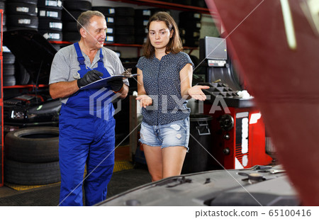mechanic standing with client, writing job sheet for repairs mechanic standing with client, writing job sheet for repairs 65100416