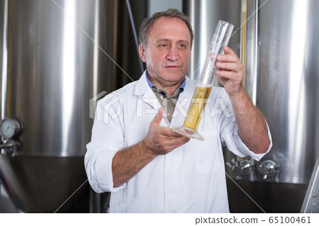 Man expert is analizying the quality of beer in flask 65100461
