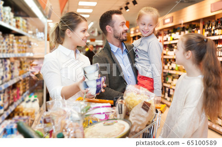 family is standing with trolley with food family is standing with trolley with food 65100589