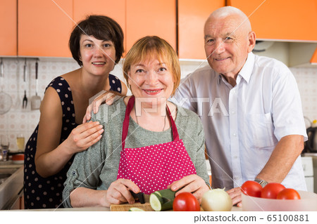 Senior couple and their daughter cooking 65100881