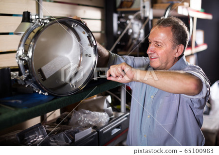 Smiling male is repairing instruments in workshop 65100983