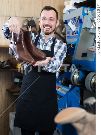Smiling male worker showing fixed shoes Smiling male worker showing fixed shoes 65101017