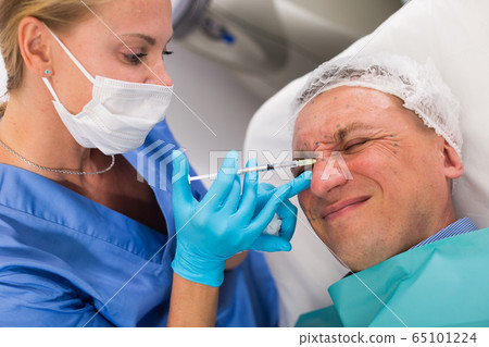 Female doctor is doing injection to patient in skin of face 65101224