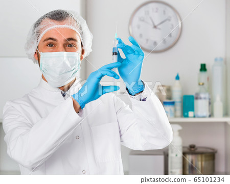 Man nurse preparing syringe for injection in hospital Man nurse preparing syringe for injection in hospital 65101234