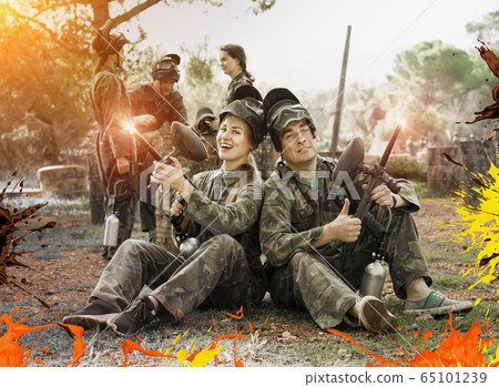 Man and woman paintball players in camouflages with masks and ma 65101239