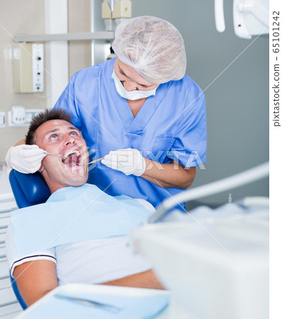 Female dentist with male patient during сheckup Female dentist with male patient during сheckup 65101242