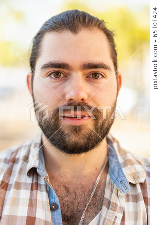 Portrait of an attractive man standing on street in a plaid shirt Portrait of an attractive man standing on street in a plaid shirt 65101424