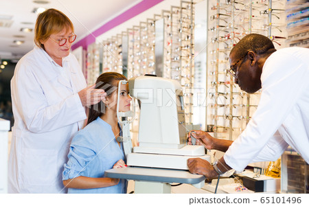 Two optometrists testing eyesight of woman 65101496