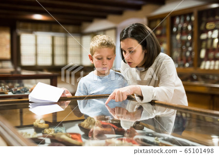 Woman and boy exploring artworks in museum 65101498