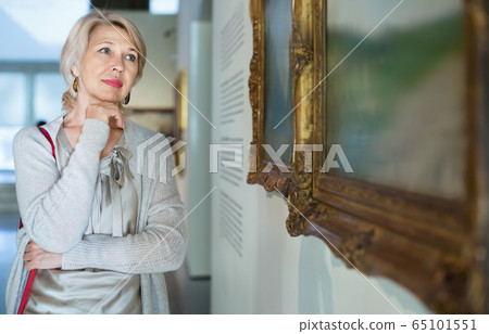 Female visitor looking at artwork painting in the museum indoors Female visitor looking at artwork painting in the museum indoors 65101551