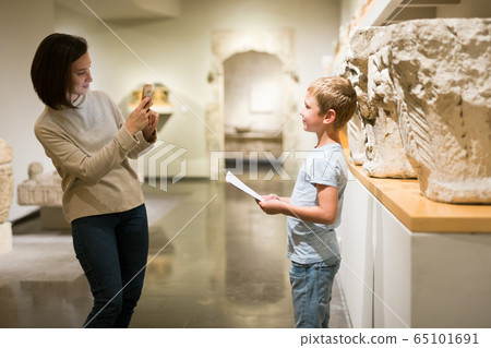 Woman using phone in museum 65101691