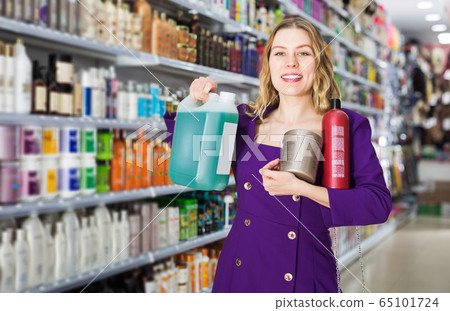 saleswoman offering modern hair care products in cosmetic shop 65101724