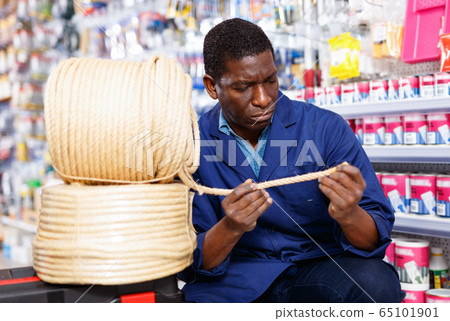 Confident African-American handyman choosing materials for overhauls in household store 65101901