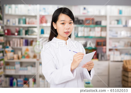 Chinese female is checking medicine with notebook in pharmacy Chinese female is checking medicine with notebook in pharmacy 65102033