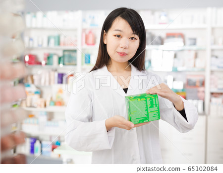 Chinese female pharmacist demonstrating assortment of pharmacy Chinese female pharmacist demonstrating assortment of pharmacy 65102084