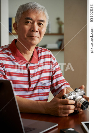 Man uploading photos from camera on laptop 65102088