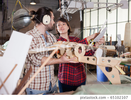 Couple checking drawings while modeling airplanes Couple checking drawings while modeling airplanes 65102107