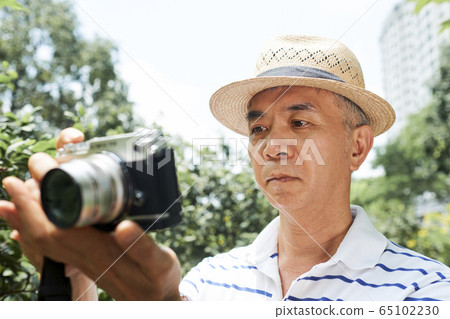 Senior man looking at screen of camera 65102230