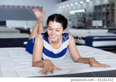 active woman is lying on bed and testing mattress for relax 65102232