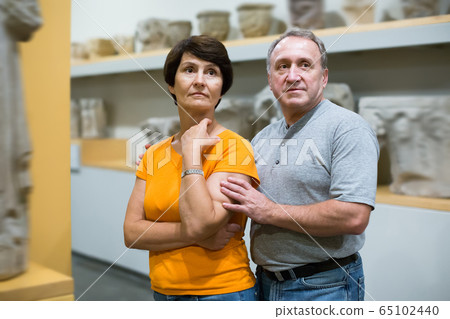 Glad man and woman looking at sculptures 65102440