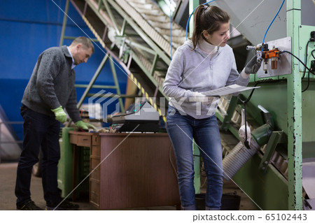 Woman supervising sensors of machine of olive oil pressing Woman supervising sensors of machine of olive oil pressing 65102443
