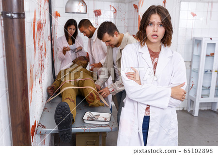 Frightened girl in escape room stylized as medical room 65102898