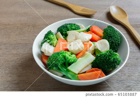 close up of stir fried broccoli with fish ball in a ceramic bowl on wooden table. close up of stir fried broccoli with fish ball in a ceramic bowl on wooden table. 65103887