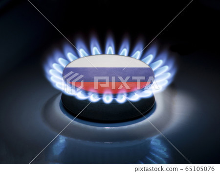 Burning gas burner of a home stove in the middle of which is the flag of the country of Russia. Gas import and export delivery concept, price per cubic meter, transit, background Burning gas burner of a home stove in the middle of which is the flag of the country of Russia. Gas import and export delivery concept, price per cubic meter, transit, background 65105076