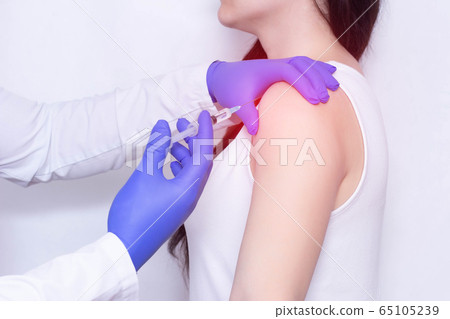 Doctor makes an injection of blockade of chondroprotector and anti-inflammatory drug in the girl's sore shoulder, white background, close-up, ozone therapy 65105239