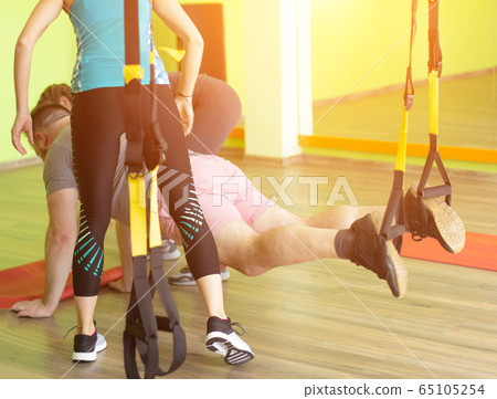 Two girls trainer teach a man to practice on the hinges of loops, weight loss, bundles 65105254