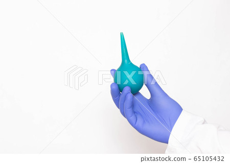 Doctor holds an enema in his hand on a white background, the concept of treating chronic prostatitis with microclysmic action on the inflamed prostate, copy space Doctor holds an enema in his hand on a white background, the concept of treating chronic prostatitis with microclysmic action on the inflamed prostate, copy space 65105432