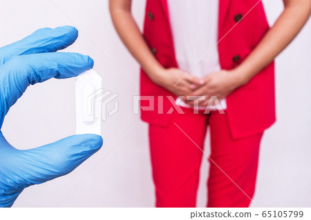 Doctor holds vaginal suppository suppository against the background of a girl who has pain and inflammation, urological infections, vaginal microflora, trichomoniasis 65105799