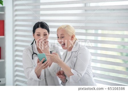 Two doctors in white robes laughing together Two doctors in white robes laughing together 65108386