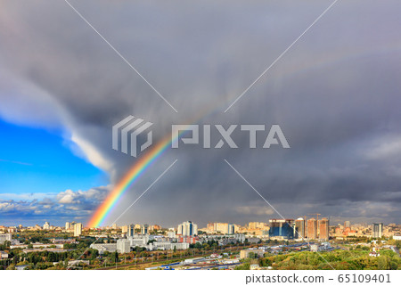 A bright rainbow in the sky above city houses A bright rainbow in the sky above city houses 65109401