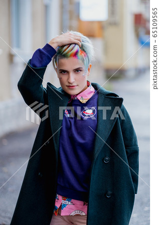 Portrait of a young beautiful woman with a short haircut and dyed hair. Grey main color and yellow, green, blue and red hair color. 65109565