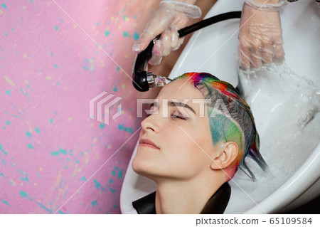 The hairdresser washes the head of a woman to a client. Colouring. 65109584