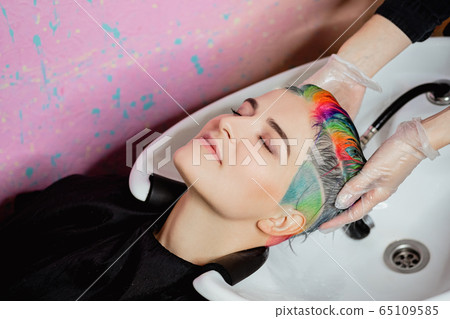 The hairdresser washes the head of a woman to a client. Colouring. 65109585