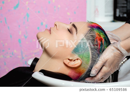 The hairdresser washes the head of a woman to a client. Colouring. 65109586
