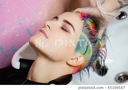 The hairdresser washes the head of a woman to a client. Colouring. 65109587
