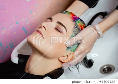 The hairdresser washes the head of a woman to a client. Colouring. 65109588