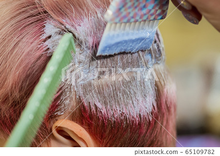 Hairdresser colorist dyes the hair of a woman to a client in different colors. 65109782