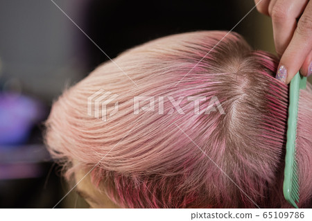 Hairdresser colorist dyes the hair of a woman to a client in different colors. Hairdresser colorist dyes the hair of a woman to a client in different colors. 65109786