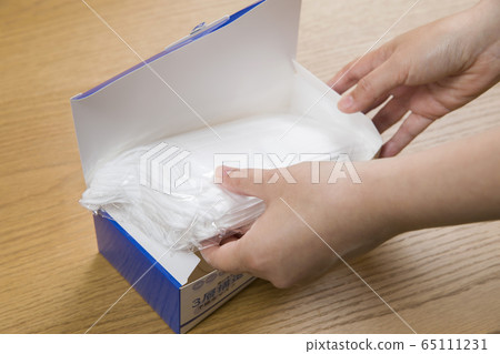 Female hand to take out the mask from the box and check 65111231