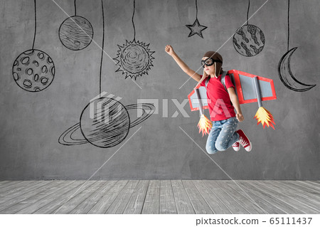 Happy child with toy paper wings playing at home 65111437