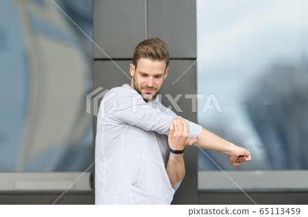 Man athlete concentrated face stretching arms 65113459