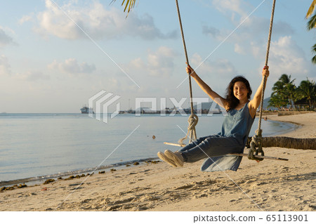 The girl on the beach rides on a swing during 65113901