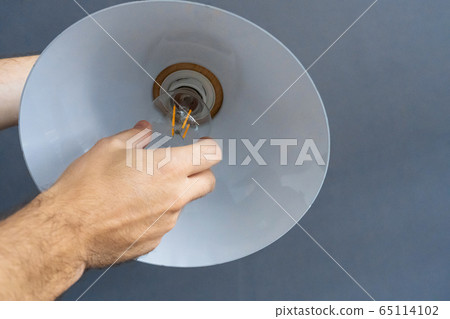 Close-up. A hand changes a light bulb in a stylish Close-up. A hand changes a light bulb in a stylish 65114102