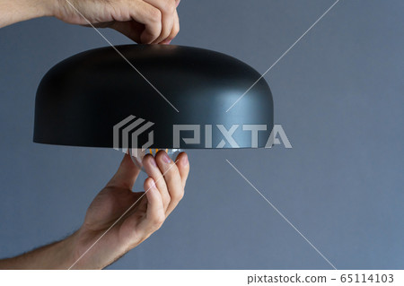 Close-up. A hand changes a light bulb in a stylish Close-up. A hand changes a light bulb in a stylish 65114103